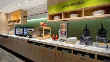 A breakfast bar with a 'Good Morning' sign, a self-serve coffee station, and a display of breakfast items.