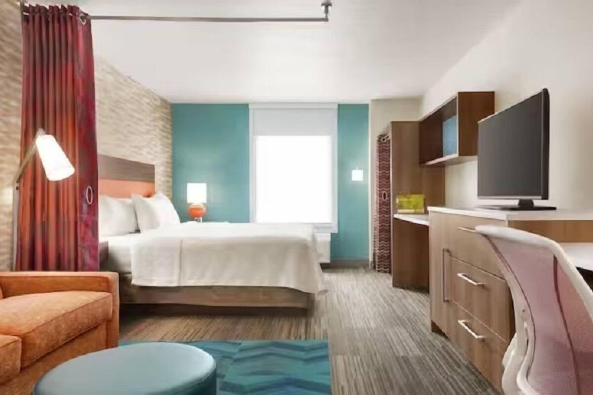 Une chambre d’hôtel comprenant un lit, un bureau, une chaise, une télévision et un canapé.