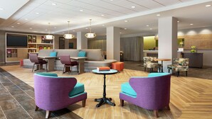 Un hall d’entrée spacieux, avec un canapé, des fauteuils, une table basse et un comptoir de réception.