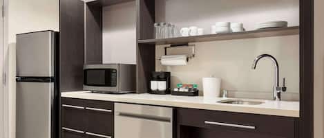 A modern kitchen with a built-in microwave, coffee maker, and stainless steel refrigerator.