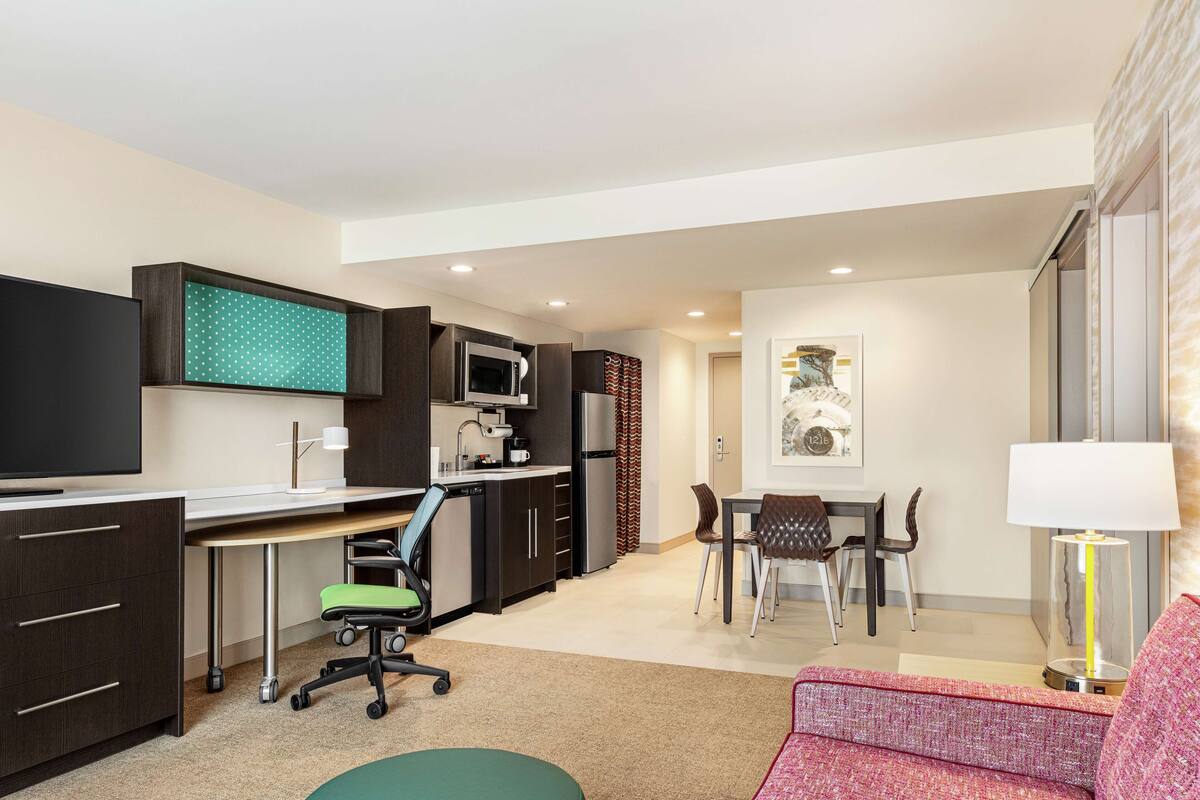 Een modern appartement met een kitchenette, een eethoek, een woonkamer met een bank en een televisie.