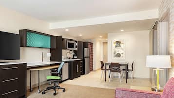 Un apartamento moderno con kitchenette, comedor, sala de estar con sofá y televisor.