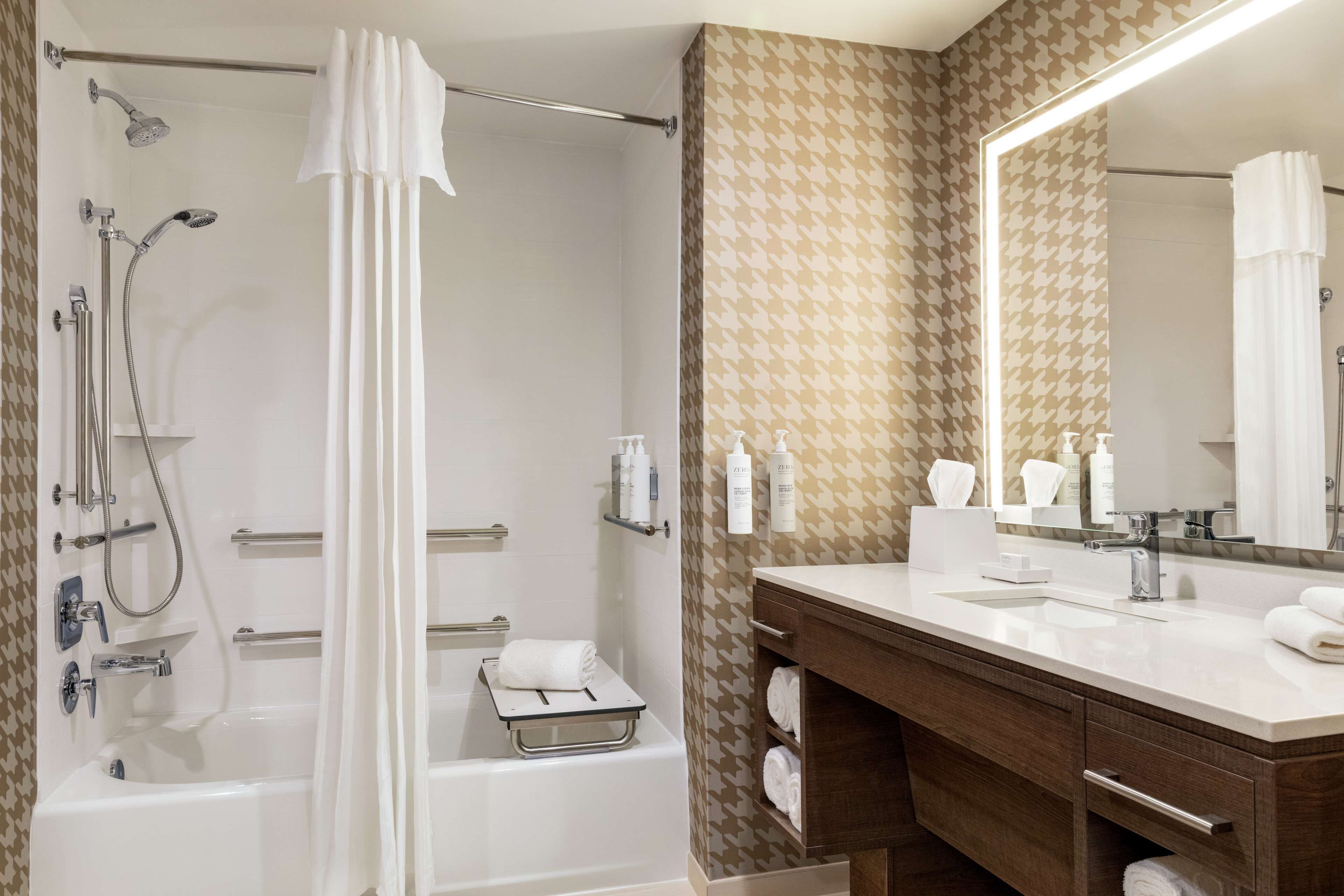 Une salle de bain moderne équipée d’une baignoire, d’une douche, d’un meuble-lavabo et d’un grand miroir.