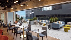 A modern lounge area with seating, tables, and potted plants.