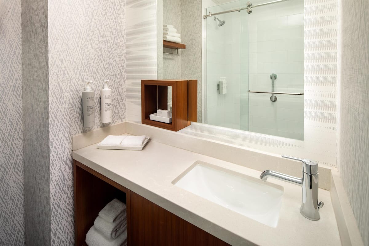 A modern bathroom with a large mirror, a sink, and a shower area.