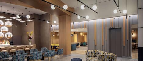 A modern lobby with a bar area, seating arrangements, and a reception desk.