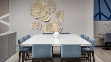 Un comedor moderno con una mesa de mármol, sillas tapizadas en azul y decoración mural.
