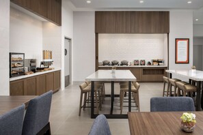 A modern kitchen with a central island, bar stools, and a breakfast bar. - Hilton Garden Inn Pensacola Downtown (Pensacola)