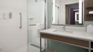 Un baño moderno con cabina de ducha de vidrio, un lavabo blanco y un espejo grande.