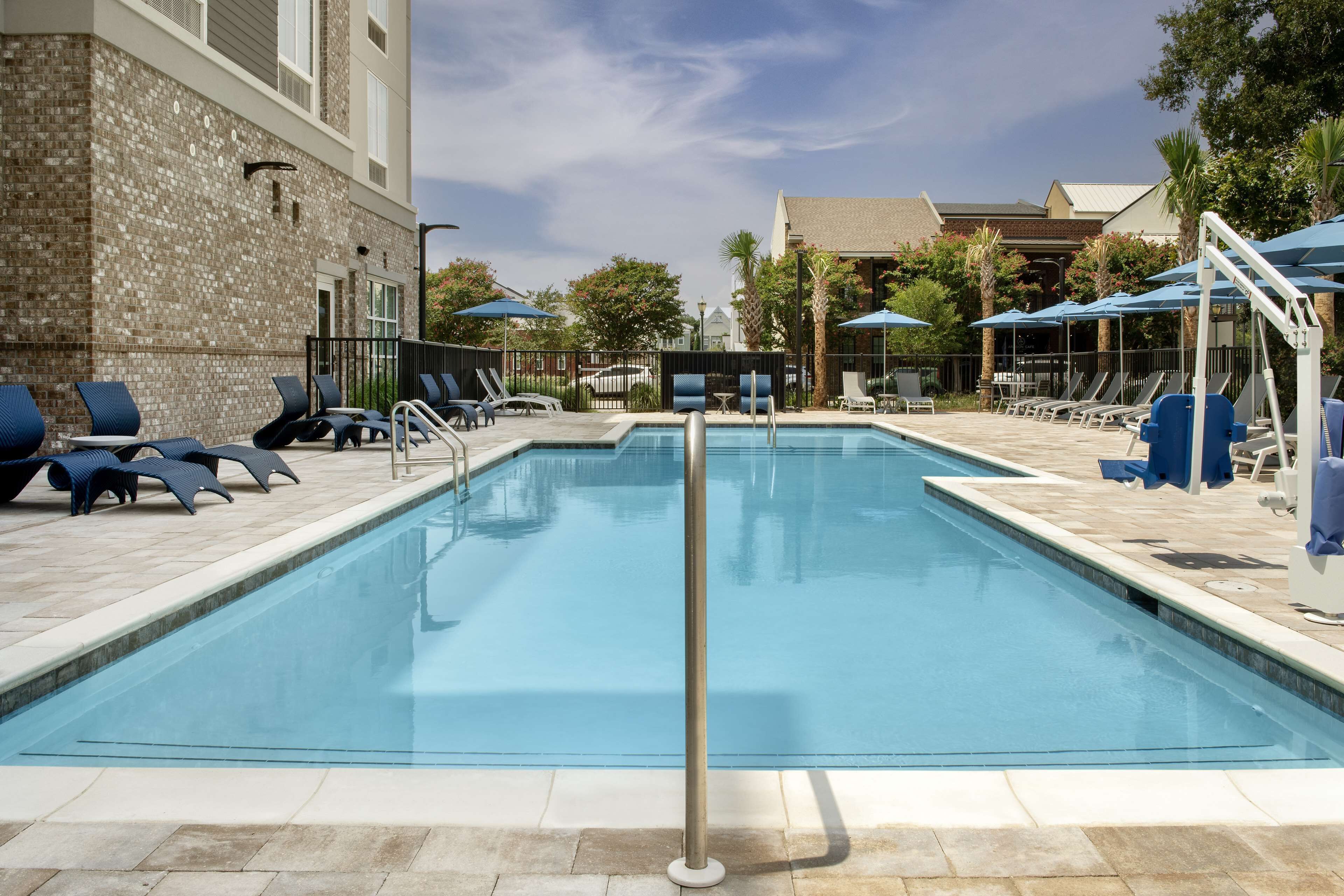 A rectangular pool with a clear blue water surface, surrounded by lounge chairs and umbrellas.