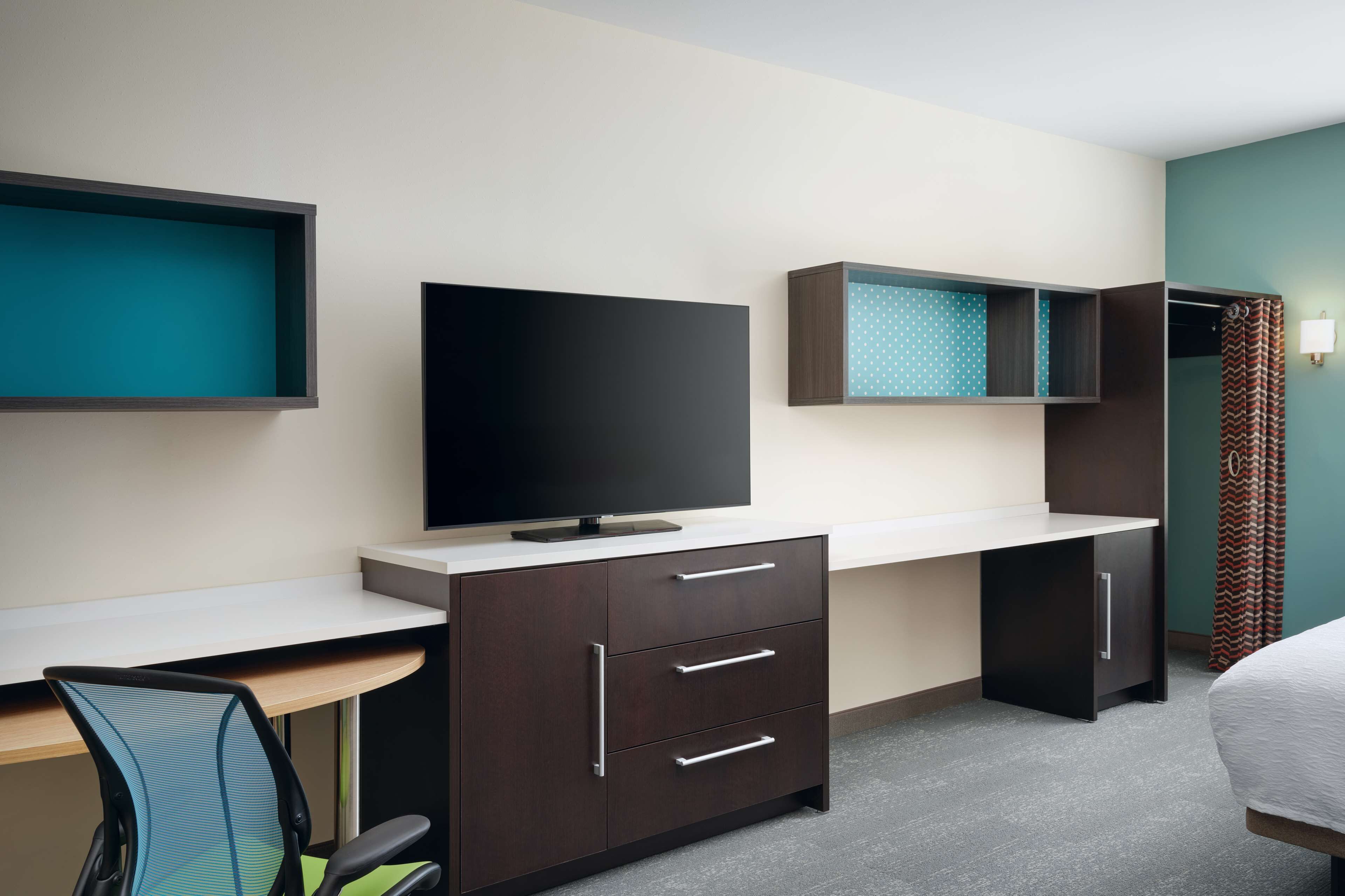A hotel room with a desk, a television, a bed, and a wardrobe.