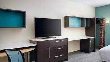 A hotel room with a desk, a television, a bed, and a wardrobe.
