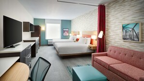 Habitación de hotel con cama, sofá, escritorio y televisor, además de una silla.