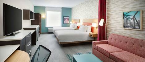 Ein Hotelzimmer mit einem Bett, einer Couch, einem Schreibtisch mit Fernseher und einem Sessel.