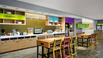 Um restaurante moderno com mesas e cadeiras de madeira, um balcão com alimentos e uma placa que diz 'inspired table'.