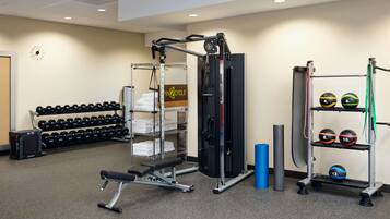 A gym with weightlifting equipment, dumbbells, and exercise balls.