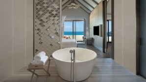 Un baño moderno con una bañera grande, ducha y vistas a la playa.