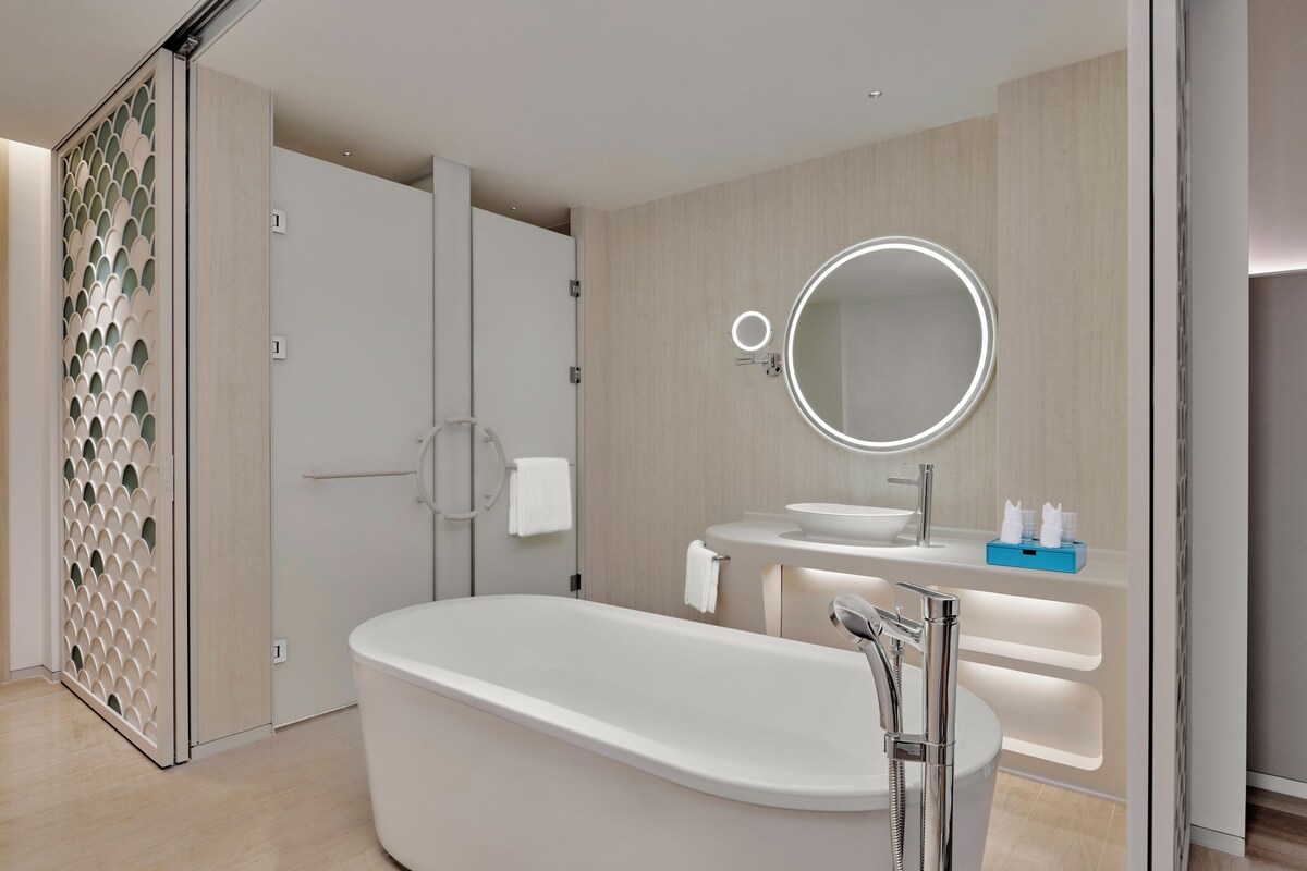 Un baño moderno con una bañera independiente, un tocador con espejo y una cabina de ducha.