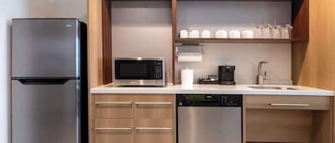 A modern kitchen with a stainless steel refrigerator, a microwave, a coffee maker, and a dishwasher.