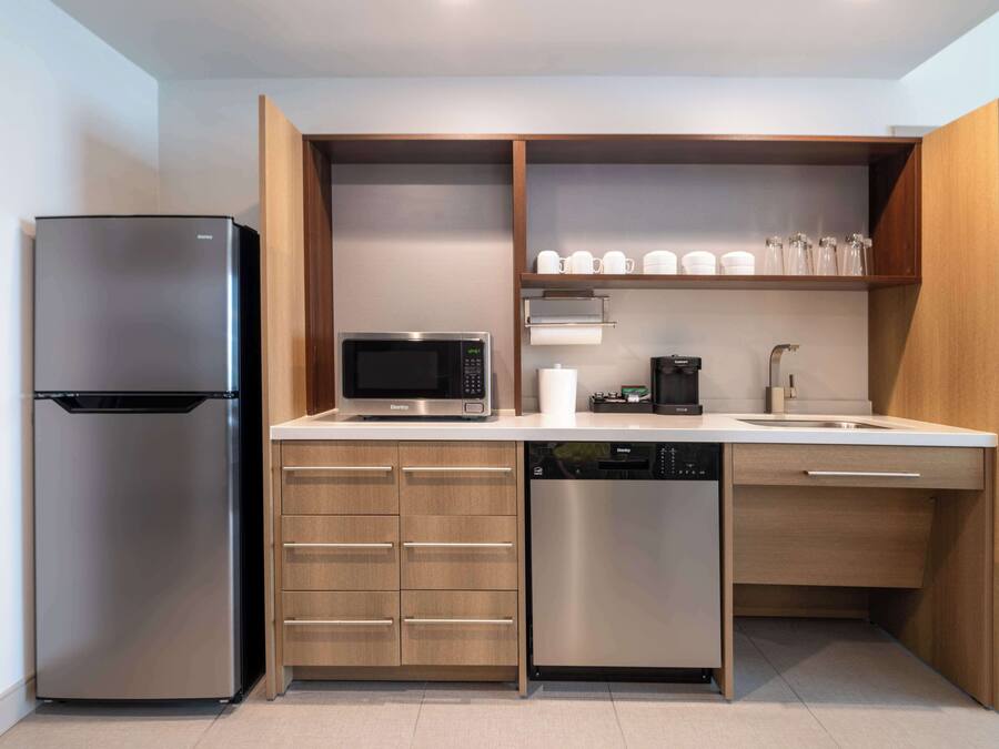 Una cocina moderna con un refrigerador de acero inoxidable, microondas, cafetera y lavavajillas.