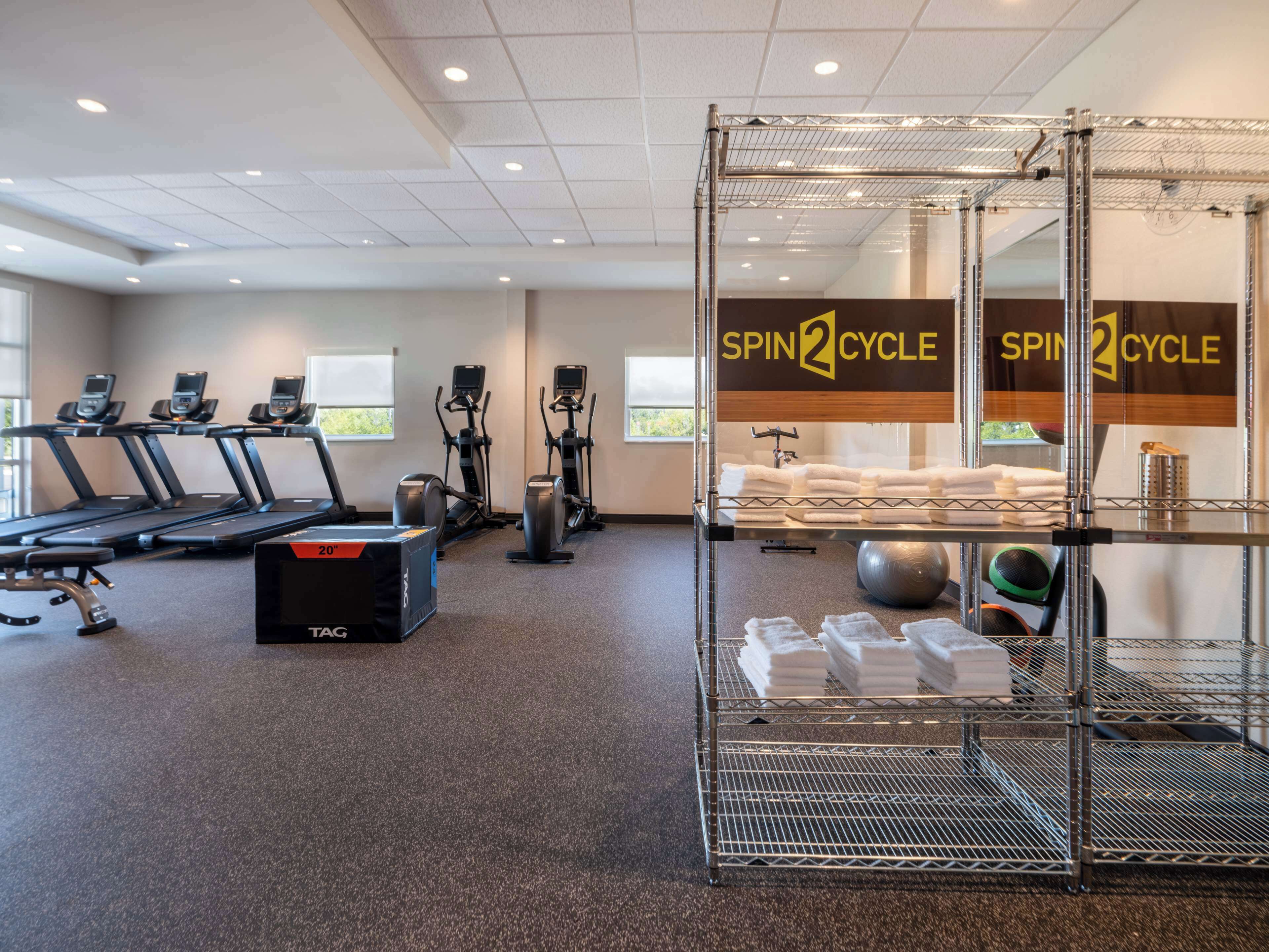 Un gimnasio con cintas de correr, elípticas y una zona de ciclismo indoor.