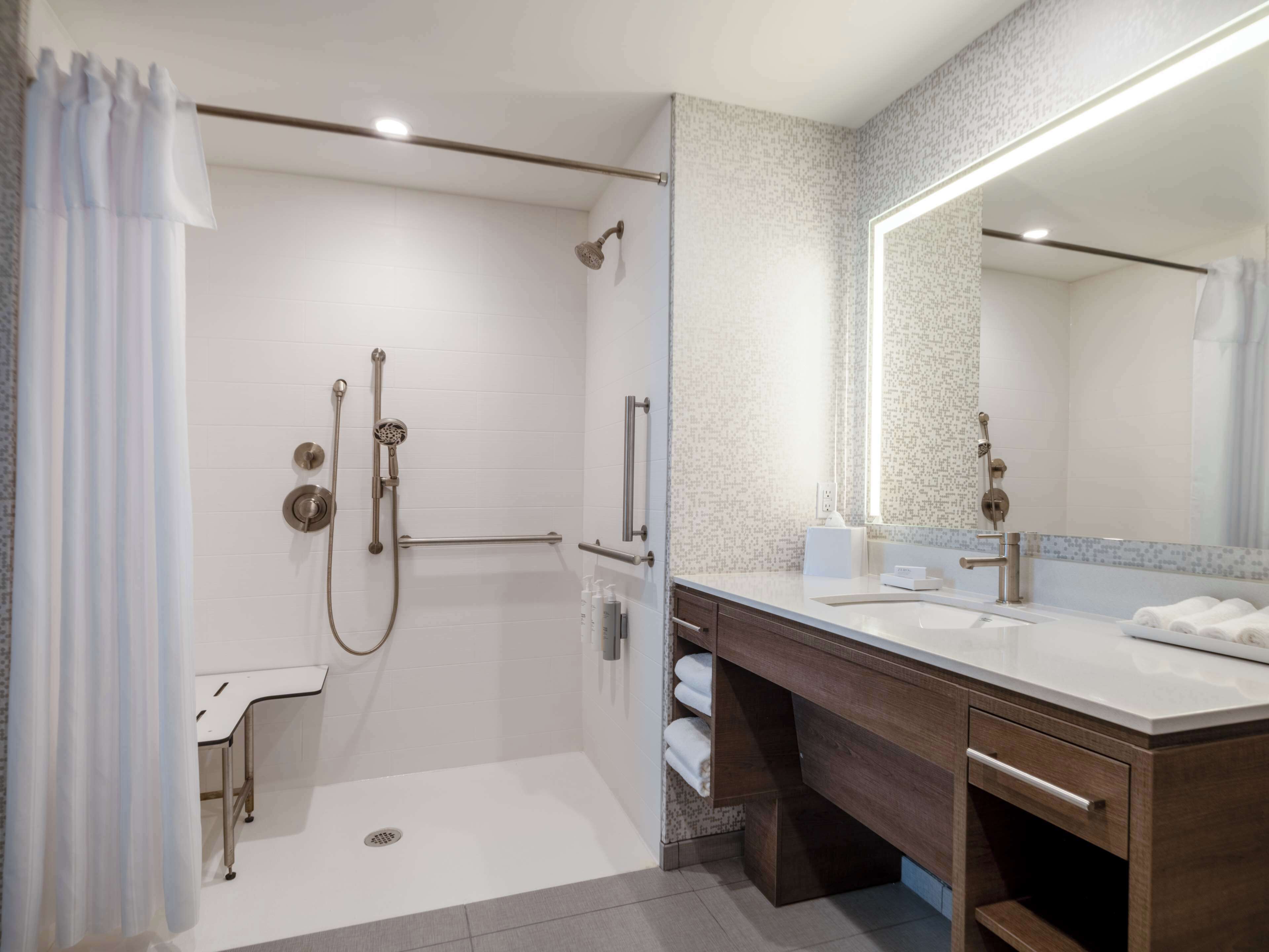 A modern bathroom with a walk-in shower, a vanity with a mirror, and a toilet.