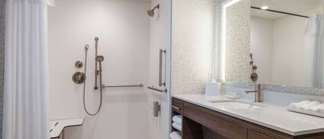 A modern bathroom with a walk-in shower, a vanity with a mirror, and a toilet.