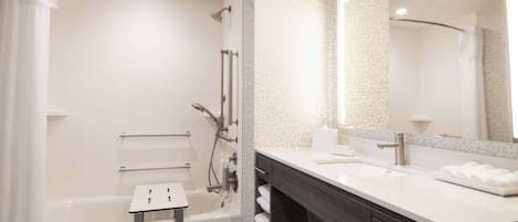A modern bathroom with a bathtub, a vanity with a mirror, and a shower area.