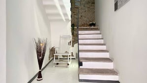 A staircase with white steps leading to a landing. There is a white chair and a decorative vase on the landing. - Ca Sistina Blue (Morcote)