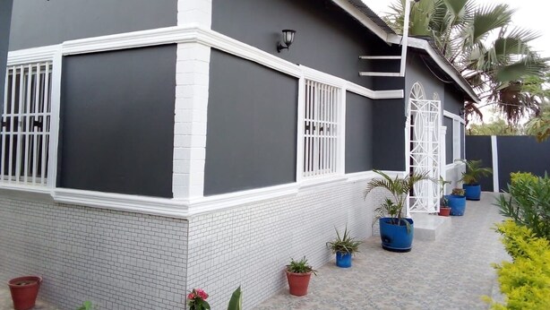 A modern house with a grey and white exterior, white window frames, and a tiled entrance. - 3 beds 3 bathrooms 5mins from turntable , close to few corner shops and beaches (Brufut)