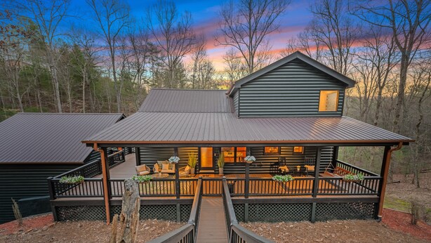 A log cabin with a wooden deck and a staircase leading to the entrance.