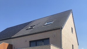 A modern two-story building with a brick facade, large windows, and a covered garage.