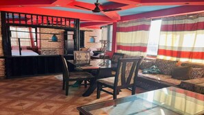 Um quarto com uma mesa de jantar, cadeiras, um sofá e uma janela com cortinas listradas.