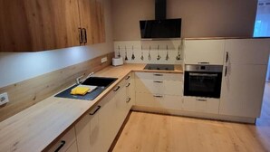 Eine moderne Küche mit Holzausstattung, einem Backofen und einer schwarzen Dunstabzugshaube.