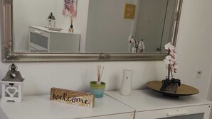 Een witte ladekast met een grote spiegel en een decoratief welkomstbord.