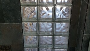 Un baño con pared de azulejos y separador de vidrio.