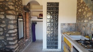 Una cocina estrecha con pared de ladrillo, salpicadero de azulejos y estufa a gas.