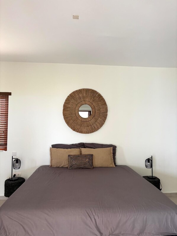 A bedroom with a large bed, a round mirror on the wall, and two bedside lamps. - Amazing seaview close to beach (Curaçao)