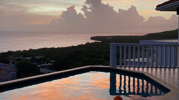 Una piscina con vistas al mar y al atardecer.