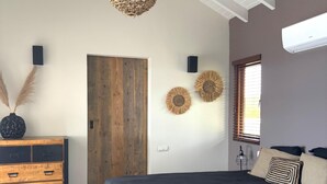 Een slaapkamer met een groot bed, een houten dressoir en een plafondventilator.