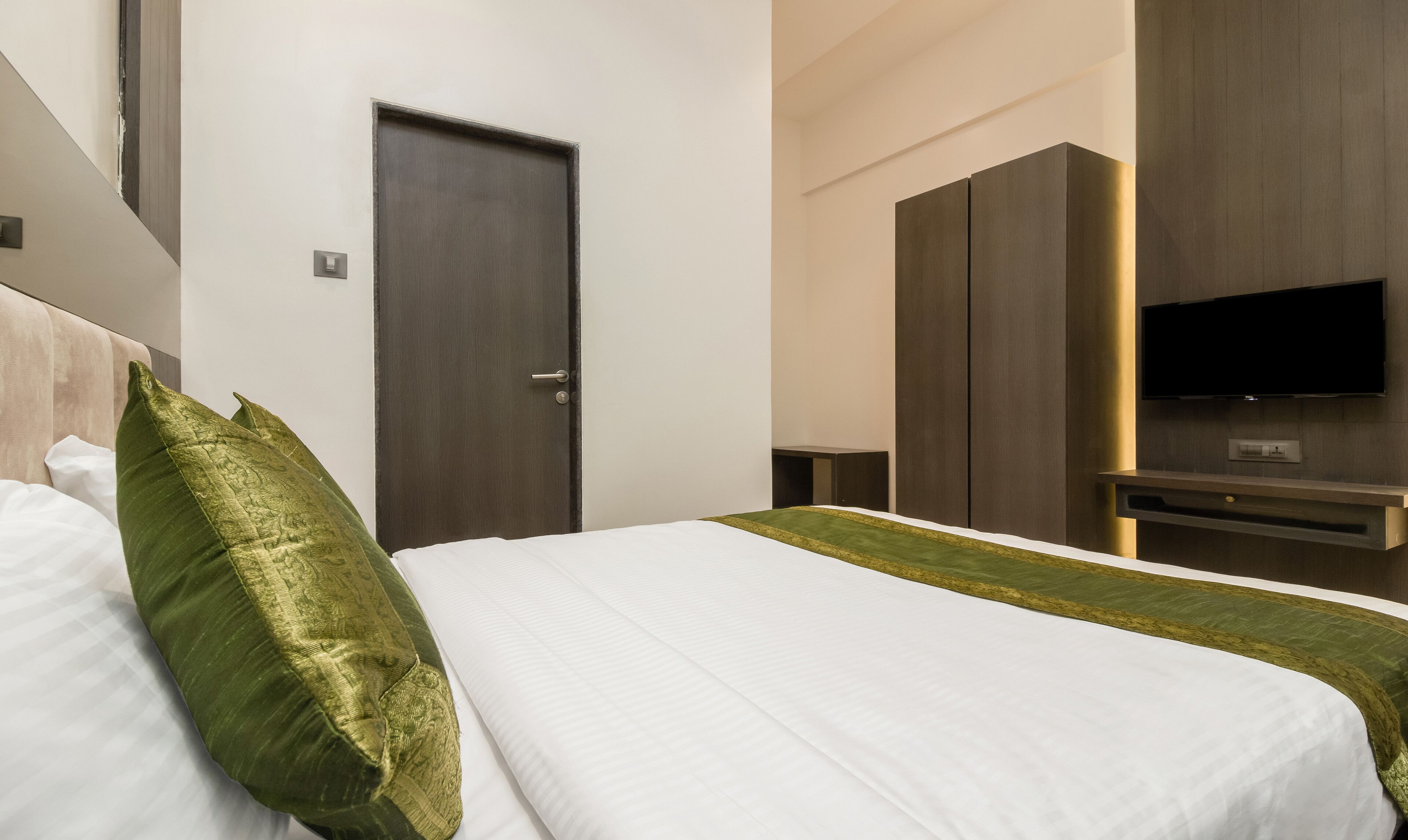 Een hotelkamer met een bed, een deur, een televisie en een kledingkast.
