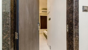 Un pasillo de hotel con una cama, un equipo de aire acondicionado y una puerta con manija.