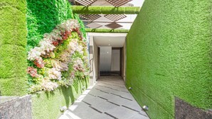 Un pasillo con paredes de césped artificial verde y suelo de baldosas.