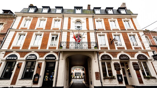 Un edificio de varios pisos con una entrada central, mostrando carteles que dicen 'Bistro Lambert' y 'Bistronomie'.