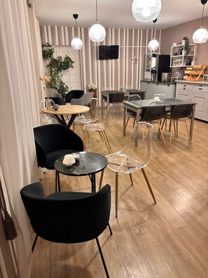 Un comedor moderno con mesas redondas, sillas transparentes e iluminación colgante.