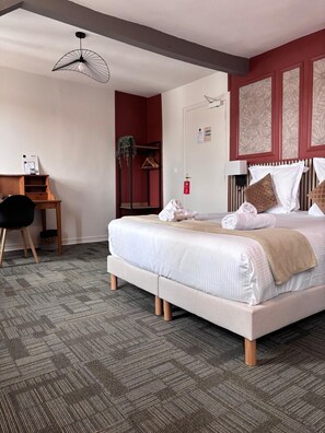 Una habitación de hotel con cama, escritorio, silla y una planta colgante.