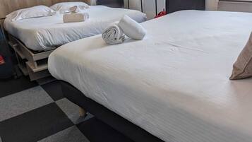 A hotel room with two beds, a checkered floor, a suitcase, and a pair of shoes.