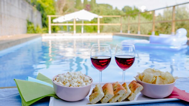 Escena junto a la piscina con una mesa que ofrece aperitivos y bebidas.