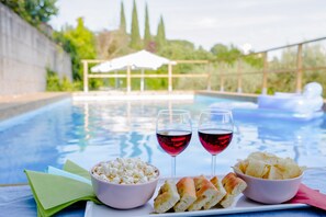 Un espace aménagé au bord de la piscine, avec une table où sont disposés des collations et des boissons.