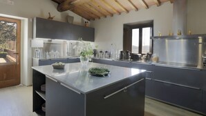 Una cocina moderna con una isla central, electrodomésticos integrados y techo de madera.